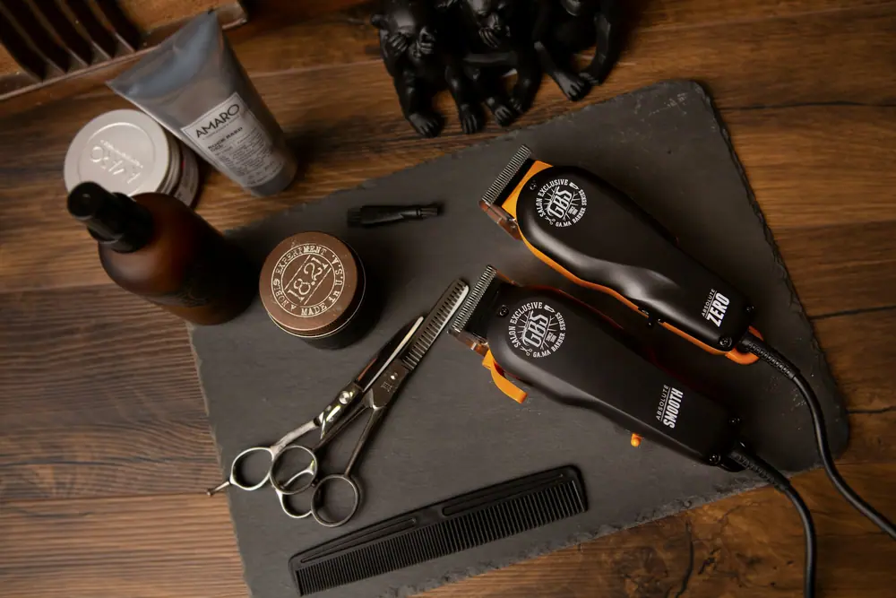 Clippers, scissors, a comb and grooming products laid out on a slate board