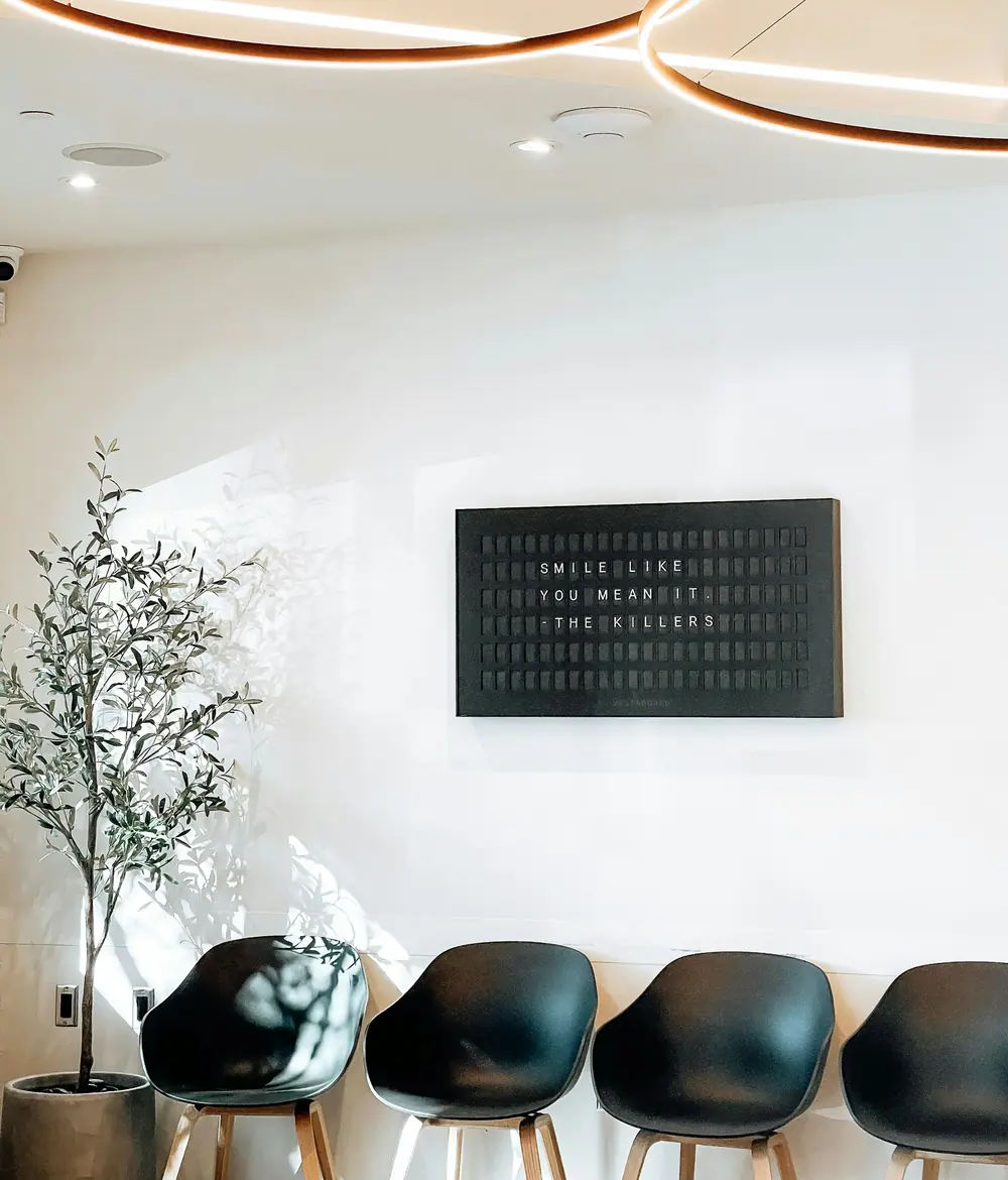 The waiting room at Lumiere, pale walls, dark stools and an olive tree