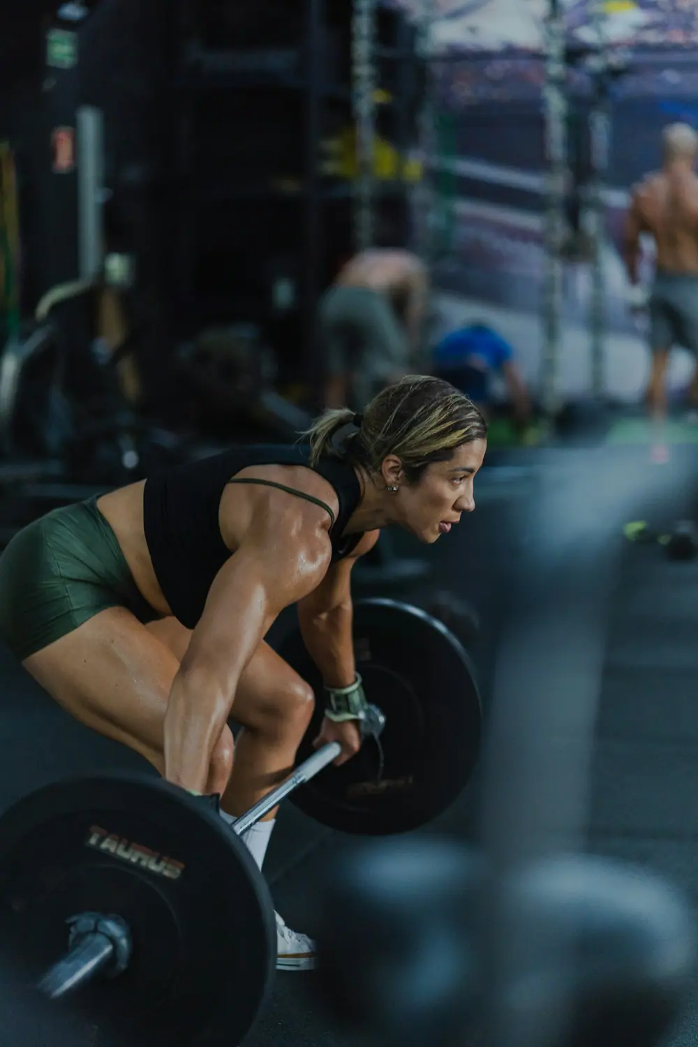 A lifter pulling a loaded barbell in the gym