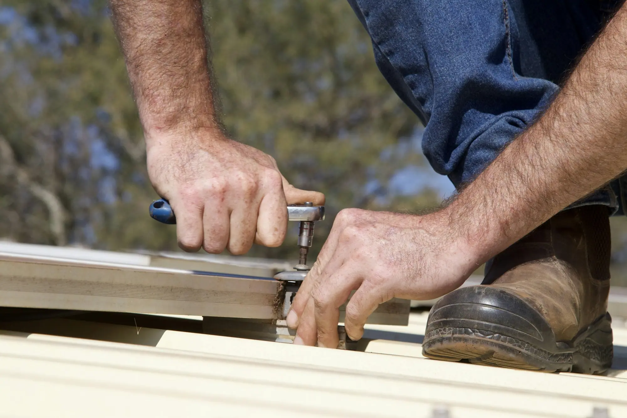 A roofer fixing the metal edge detail at the eaves of a roof