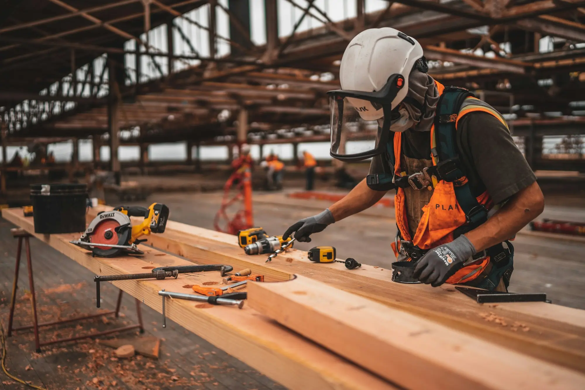 Tradesman in full protective equipment cutting timber on site